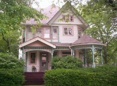 a pink house with green trim and trees