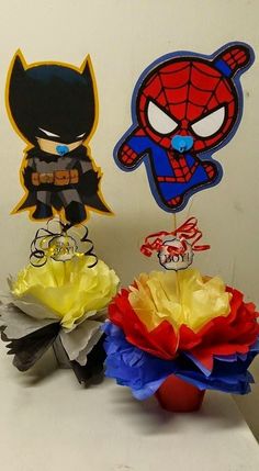 some paper flowers are sitting next to each other on a table with an image of batman and spider - man