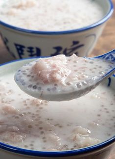 a spoon full of milk is being held over two bowls filled with oatmeal