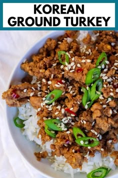 a white bowl filled with rice and meat covered in sesame seeds, green peppers and ground turkey