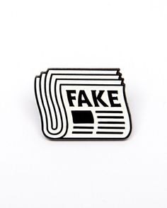 a fake newspaper pin sitting on top of a white surface with the word fake in it