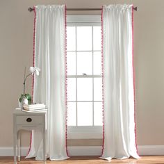 a window with white curtains and pink trim on the edges, in front of a table