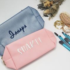 two personalized makeup bags sitting on top of a table next to brushes and other items