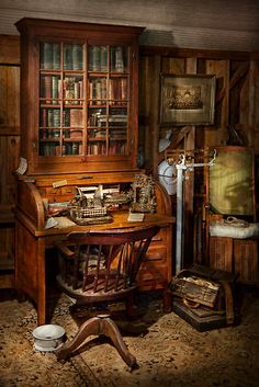 an old fashioned desk and bookshelf in a room with wood paneled walls