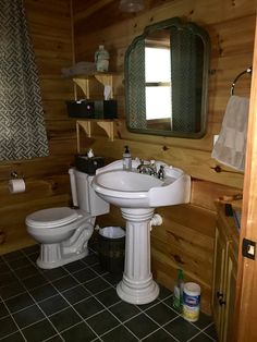 a white toilet sitting next to a sink in a bathroom on top of a tiled floor