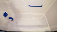 a white bath tub with blue handles in a bathroom