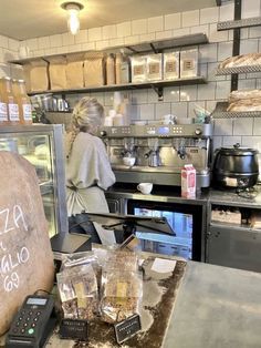 a woman standing in a kitchen next to a counter with food on top of it