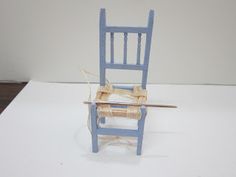 a miniature blue chair with a knife stuck in it's back end on a white surface