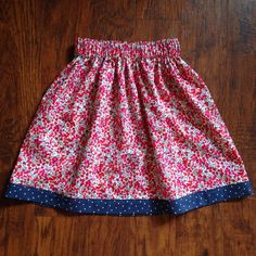 a red and blue skirt with white polka dots on it sitting on a wooden floor