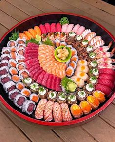 a platter filled with different types of sushi on top of a wooden table