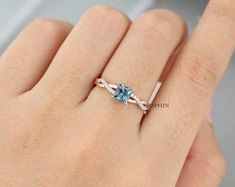 a woman's hand with a ring that has an aqua blue stone on it