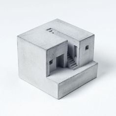 a small house made out of concrete on a white surface