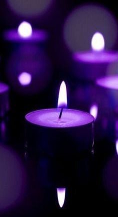 many lit candles with purple lights in the background