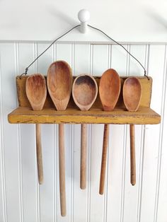 five wooden spoons are hanging on a wall