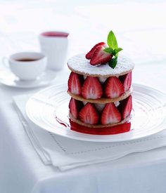 a stack of strawberry shortcakes sitting on top of a white plate