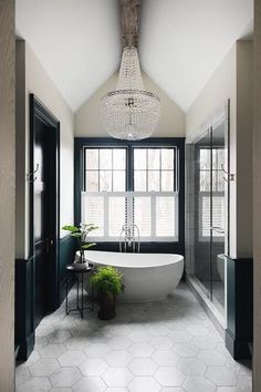 the bathroom is decorated in black and white with a chandelier over the bathtub