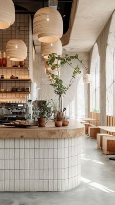 the interior of a restaurant with white tiled walls and wooden tables, potted plants on the counter