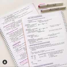 two notebooks sitting next to each other on top of a white table with pens