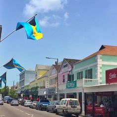 cars parked on the street in front of shops and buildings with flags flying above them