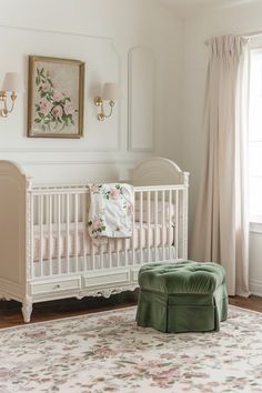 a baby's room with a white crib and pink flowers on the wall