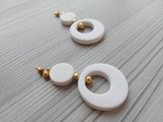 two pairs of white and gold earrings sitting on top of a table