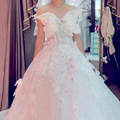 a woman in a pink and white wedding dress standing in front of a mirror