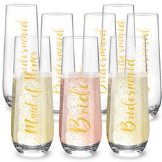 six champagne flutes with gold lettering and confetti in the bottom are lined up