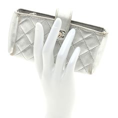 This is an authentic CHANEL Metallic Lambskin Quilted Mini Phone Holder Clutch in Silver. This chic phone holder is crafted of diamond quilted metallic lambskin in silver. The clutch features a cross over strap with a small polished silver CC on the front and opens to a grey fabric interior with a central zipper pocket. Mini Phone, Diamond Quilt, Grey Fabric, Phone Holder, Zipper Pocket, Chanel, Things To Sell, Zipper, Grey