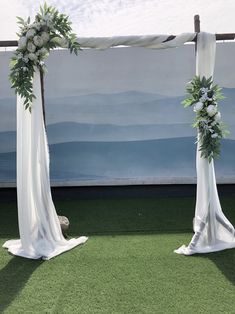 an outdoor ceremony setup with white flowers and greenery