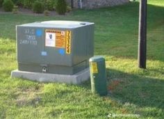 a box sitting in the grass next to a trash can