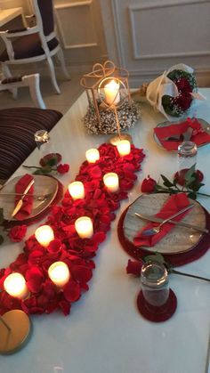 the table is set with red roses and candles for an elegant valentine's day dinner