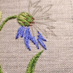 a close up view of some flowers on a piece of cloth with stitches and thread