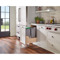 a kitchen with white cabinets and wood flooring has an open dishwasher in the middle