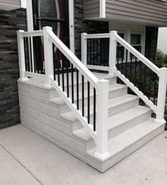 a white stair case next to a black door on a house's front porch