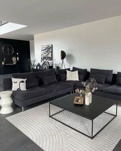 a living room filled with black couches and white rugs