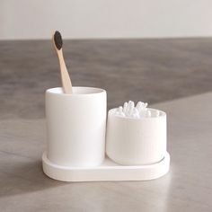 a toothbrush and cup sitting on a counter top next to each other, with the brush in it's holder