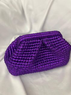 a purple purse sitting on top of a white sheet