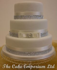 a three tiered wedding cake with white frosting and silver decorations on the top