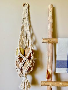 a macrame hanging on the wall next to a towel rack with two apples in it