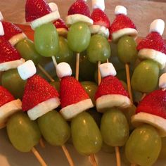 green grapes and strawberries with santa hats on them are arranged in a bowl for an appetizer