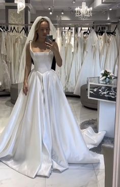 a woman is taking a selfie in front of her wedding dress on the phone