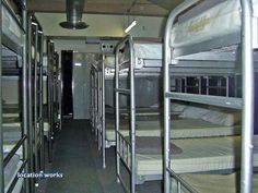 there are many bunk beds in this train car that is full of mattresses and blankets