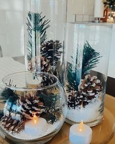 two clear vases filled with pine cones and candles