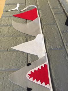 some felt shark decorations are on the floor next to a brick wall with white and red trim