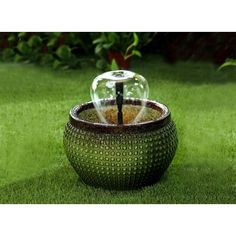 a glass ball fountain sitting on top of a lush green field