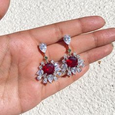 Ruby Earrings featuring semi precious red stones and cz diamonds. Perfect for any special occasion look or a wedding bridesmaid look. These Purple Dangle Earrings surely add a touch of super luxury in your entire look. Also a perfect gift for her or gift for mom. *𝐏𝐑𝐎𝐃𝐔𝐂𝐓 𝐃𝐄𝐓𝐀𝐈𝐋* * 𝐌𝐚𝐭𝐞𝐫𝐢𝐚𝐥: Brass * 𝐏𝐥𝐚𝐭𝐢𝐧𝐠: White Rhodium Plated * 𝐒𝐭𝐨𝐧𝐞: AAA-quality CZ diamond. *𝐃𝐈𝐌𝐄𝐍𝐒𝐈𝐎𝐍𝐒* * 𝐖𝐞𝐢𝐠𝐡𝐭: 8 gm each * 𝐋𝐞𝐧𝐠𝐭𝐡: 1.3 Inches * 𝐖𝐢𝐝𝐭𝐡:  0.8 Inches * Red Diamond Drop Earrings, Red Ruby Diamond Earrings For Wedding, Red Diamond Drop Earrings For Formal Events, Red Diamond Drop Earrings For Formal Occasions, Formal Red Diamond Drop Earrings, Red Diamond Earrings For Wedding, Red Synthetic Ruby Earrings, Dazzling Red Earrings For Formal Occasions, Elegant Red Cluster Earrings For Wedding