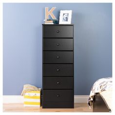 a tall black dresser sitting next to a blue wall