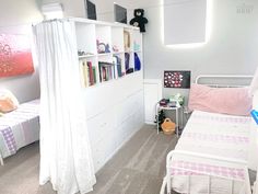 a bedroom with two beds and a white book shelf in the corner next to each other