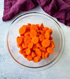 a glass bowl filled with sliced up carrots on top of a white tablecloth