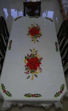 the table cloth is decorated with poinsettis and holly berries on white linen